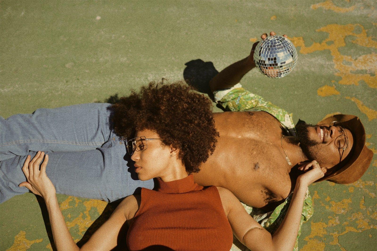 Två personer ligger på en gräsmatta i solen.